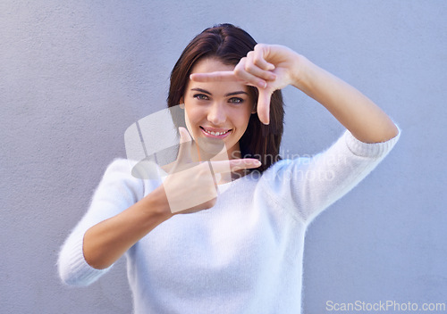 Image of Portrait, wall and woman with finger frame, smile and focus for creative fashion photography. Perspective, hand gesture and girl showing happy face, casual style and view finder on blue background.