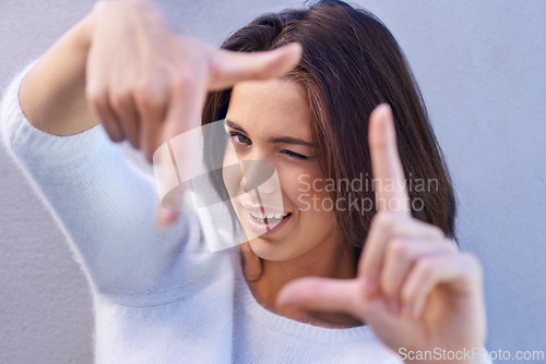 Image of Happy woman, portrait and framing face with hands for photography, selfie or capture on a gray studio background. Young female person or model with smile or frame for picture moment, memory or photo