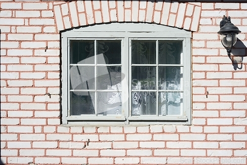 Image of old window in a brick house and a lantern on the wall