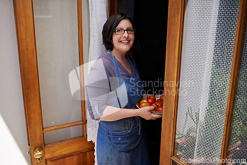 Image of Portrait, smile and woman with tomatoes in doorway of home for agriculture, farming or sustainability. Farmer, gardening and growth with happy mature person in apartment greenhouse for diet or health