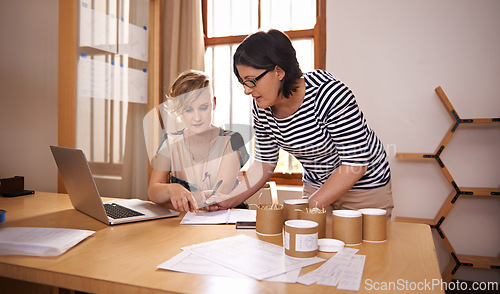 Image of Teamwork, laptop and writing with designer women in office together for planning or strategy. Computer, documents and collaboration with creative people in startup business for research or discussion