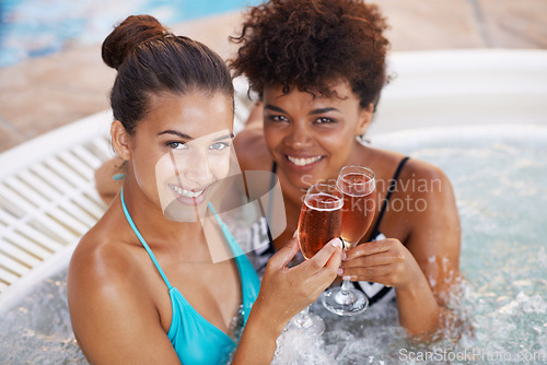 Image of Women, friends and wine in jacuzzi at spa, self care and pamper day portrait for wellness and cold beverage. Water, bubbles and alcohol or Champagne in hot tub, detox and friendship date for bonding