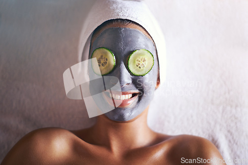 Image of Woman, face mask and smile with skin glow and cucumber for facial, spa wellness and beauty treatment. Above, towel and calm female person with skincare and relax at hotel with cosmetic cream