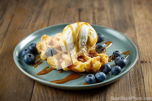 Image of plate of belgian waffle with caramel sauce and blueberries