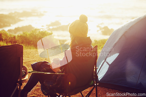 Image of Sunset, camping and woman by tent on vacation, adventure or holiday in nature for travel. Evening, coffee and back of female person relaxing and drinking cappuccino in chair outdoor for weekend trip.