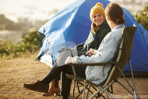 Image of Conversation, camping and couple by tent on vacation, adventure or holiday in woods. Smile, love and young man and woman talking, bonding and relaxing in outdoor forest for weekend trip in nature.