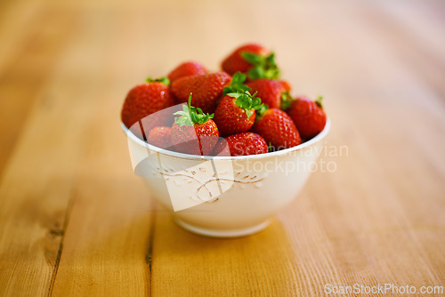 Image of Wellness, health and strawberry bowl in kitchen of home, on wooden counter top for diet or nutrition. Food, fruit and lose weight with berries on surface in apartment for detox, minerals or vitamins