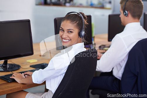 Image of Help desk, portrait and phone call with woman, typing on computer and consultant at customer support. Headset, telemarketing and client service agent at callcenter with teamwork in coworking space