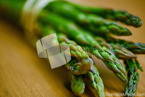 Image of Asparagus, closeup and counter for health, wellness or organic diet on wood countertop. Vegetable, nutrition or produce for eating, gourmet and meal or cuisine with vitamins or fibre for weight loss