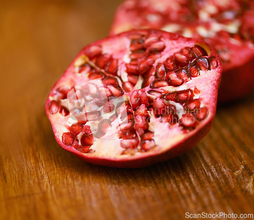 Image of Wellness, fruit and pomegranate on wooden table in kitchen for diet, health or nutrition closeup. Food, minerals and vitamins with healthy produce on counter or surface in apartment for detox