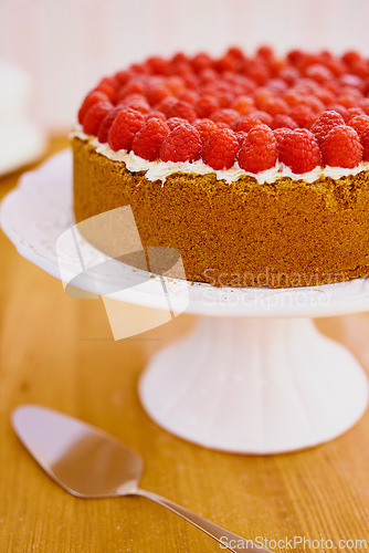 Image of Plate, spoon and cheesecake with cream and raspberries on table for sweet snack for tea time at home. Bakery, catering and gourmet dessert with crust, frosting and fresh organic fruit in dining room.