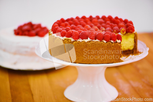 Image of Stand, slice and cheesecake with cream and raspberries on table for sweet snack for tea time at home. Bakery, catering and gourmet dessert with crust, frosting and fresh organic fruit in dining room.