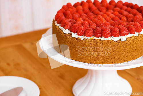 Image of Stand, cream and cheesecake with raspberries on table for sweet snack for tea time at home. Bakery, catering and closeup of gourmet dessert with crust, frosting and fresh organic fruit in dining room