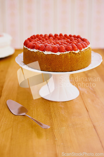 Image of Stand, spoon and cheesecake with cream and raspberries on table for sweet snack for tea time at home. Bakery, catering and gourmet dessert with crust, frosting and fresh organic fruit in dining room.