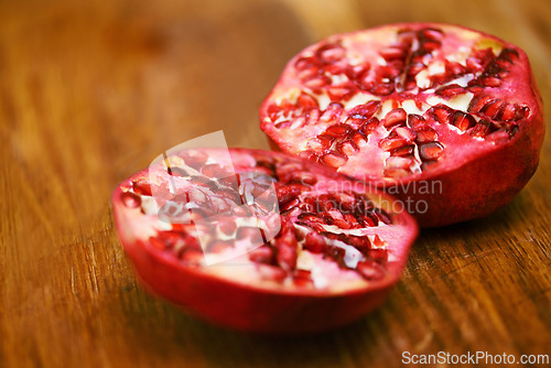 Image of Food, fruit and pomegranate on wooden table in kitchen for diet, health or nutrition closeup. Wellness, minerals and vitamins with healthy produce on counter or surface in apartment for detox