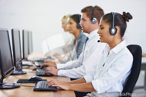 Image of Help desk, team and phone call with women, men and typing on computer at customer support. Headset, telemarketing and client service agent at callcenter with online consultation in coworking space