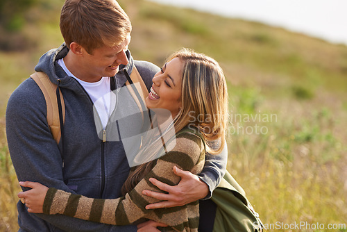 Image of Happy, love and funny couple hug in nature for hiking, bonding or fun with joke, humor or comic. Laugh, eye contact or people embrace on countryside field on adventure, journey or trekking travel