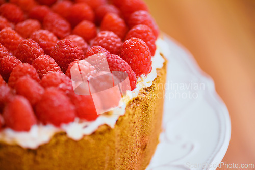 Image of Plate, frosting and cheesecake with raspberries on table for sweet snack for tea time at home. Bakery, catering and closeup of gourmet dessert with crust, cream and fresh organic fruit in dining room