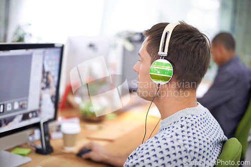 Image of Business, designer and man with headphones at computer screen in office for creative internship and web design. Employee, rear view and monitor for multimedia production and video animation at desk