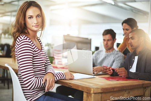 Image of Portrait, serious and business woman at office in meeting in startup company for creative career or job at table. Face, coworking and professional entrepreneur at desk, employee or designer with team