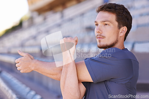 Image of Fitness, arms and man stretching in stadium for race, marathon or competition training for health. Sports, energy and male runner athlete with warm up exercise for running cardio workout on track.