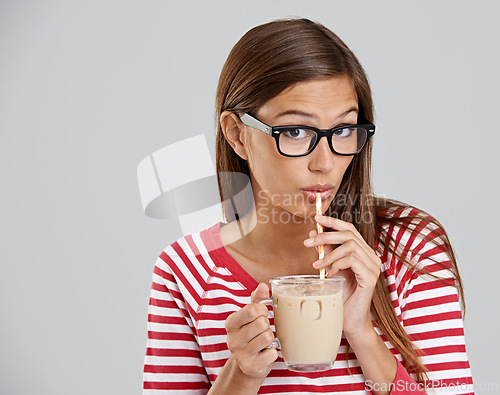 Image of Woman, portrait and iced coffee drinking in studio or sweet beverage for weekend relax, caffeine or grey background. Female person, glasses and dairy for latte smoothie, mockup space or happiness