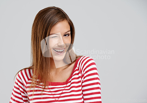 Image of Wink, portrait and girl in studio with smile for fun mood, positive attitude and mockup space. Playful, cute and happy gen z woman on white background for wellness, relax and flirt with emoji face