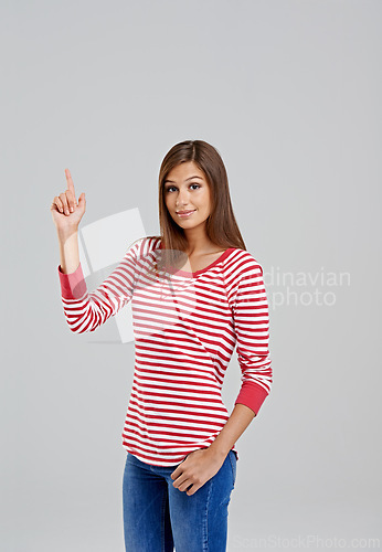 Image of Pointing, mockup and portrait of woman for fashion, style and trendy with cool outfit isolated on gray background. Female person, hand and lady with stripe shirt, blue jeans and garments in studio