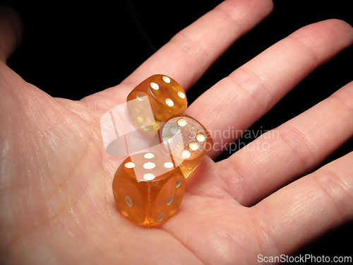 Image of Hand holding three dice on a black background