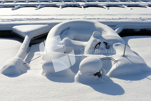 Image of boat with motor covered with snow in winter at the boat parking
