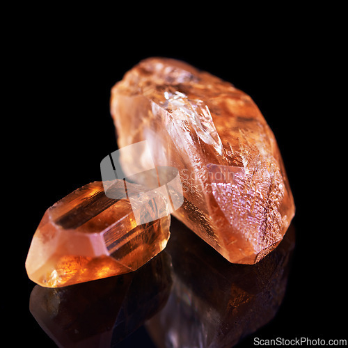 Image of Gem, rock and orange stone in studio with isolated black background for natural resource, shine and sparkle for luxury. Crystal, jewel and reflection in closeup for citrine, glow and mineral