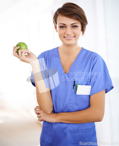 Image of Woman, nurse and happy portrait with apple in medical office, nutrition and healthy food choice, professional nursing career. Dietician, healthcare and fruit for wellness with fibre and vitamins