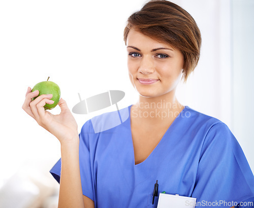 Image of Woman, nurse and smile portrait with apple in medical office, nutrition and healthy food choice, professional nursing career. Dietician, healthcare and fruit for wellness with fibre and vitamins