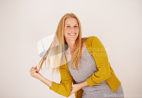 Image of Smile, fashion and portrait of woman in studio with casual, trendy and cool outfit with confidence. Happy, attractive and female person playing with hair for cardigan style by white background.