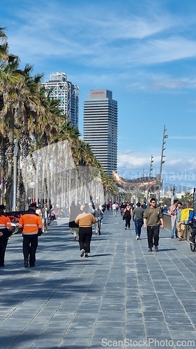 Image of BARCELONA, SPAIN - APRILL 2, 2024: Group of people walking down street next to palm trees