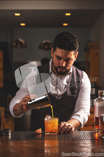 Image of Professional bartender pouring a cocktail at bar