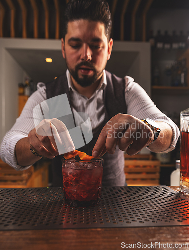 Image of Expert bartender garnishing cocktail at bar