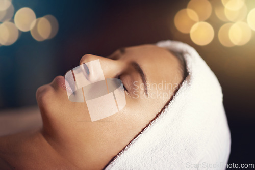 Image of Woman, relax and wellness in spa for beauty, therapy and cosmetic treatment with eyes closed for break and skincare. Young person with towel on head for peace, holistic and hygiene care on bokeh