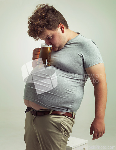 Image of Obese, weight gain and alcohol for man in studio with drink for unhealthy habit, plus size and joke. Overweight person with glass on fat stomach for balance, comedy and humor for lager and comic