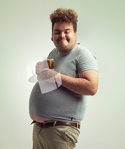 Image of Obesity, weight gain and lager for man in studio with drink for unhealthy habit, plus size and joke. Overweight person with glass on fat stomach for balance, drunk and humor for alcohol and comic