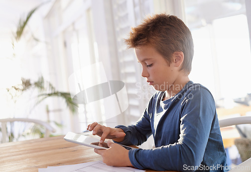 Image of Child, tablet and notes in house for homework, elearning and games on table with internet and online. Young boy or kid with technology and finger on screen for touch, scroll or study for education