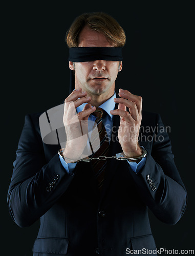 Image of Blindfold, businessman and handcuffs for corruption, fraud and white collar crime isolated on dark studio background. Male person, corporate worker and banker with scam, money laundering and bribery