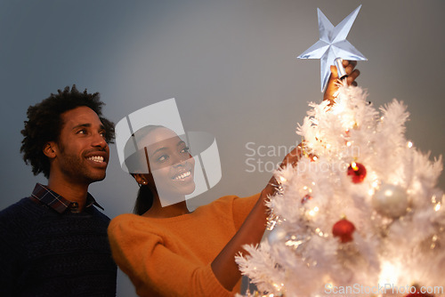 Image of Couple, Christmas and tree with star decoration for holiday celebration in winter season for festive, giving or presents. Man, woman and lights in living room for bonding vacation, event or tinsel