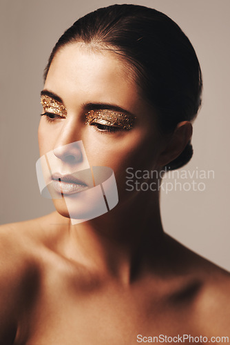 Image of Gold glitter, beauty and woman with eyeshadow, makeup and cosmetology with shimmer for shine on beige background. Glamour, sparkle and fashion model in studio, cosmetics and elegance with creativity