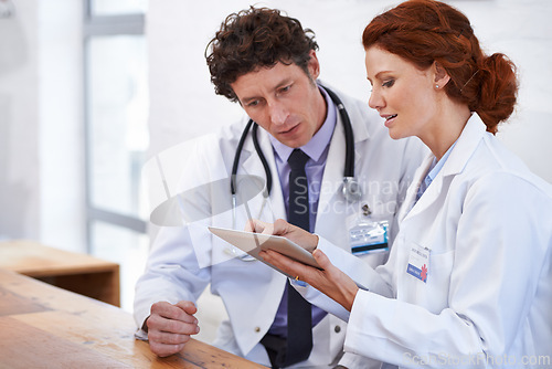 Image of Doctors, man and woman on tablet in hospital for team, planning and review for medical results. Medic employees, people and digital touchscreen in clinic for collaboration with telehealth services