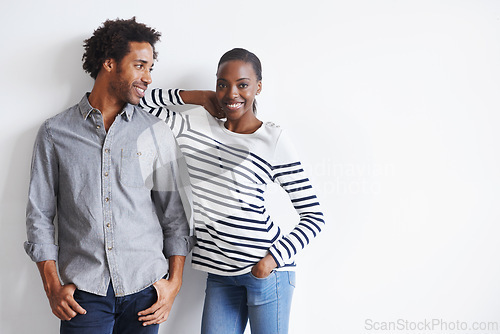 Image of Couple, smile and portrait by white wall in fashion with confidence, casual style and model aesthetic. Black woman, and face of man with trendy apparel, edgy clothes and pride with support and relax