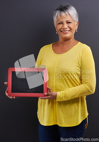 Image of Smile, chalk board and portrait of woman in studio with mockup space for marketing, promotion or advertising. Happy, mock up and senior female person with frame for news isolated by black background.