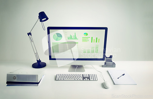 Image of Workspace, computer screen and notebook in room with light for remote work, infographics or data analytics. Workplace, monitor and documents on desk with keyboard for financial career and statistics