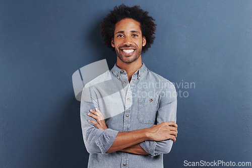 Image of Portrait, smile and black man with arms crossed, fashion and afro on a blue studio background. Face, African person and model with casual outfit and stylish clothes with confidence and mockup space