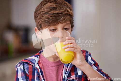 Image of Kids, kitchen and boy drinking orange juice from glass in morning for diet, health or nutrition. Breakfast, children and cup with young teen in apartment to enjoy fresh beverage for development